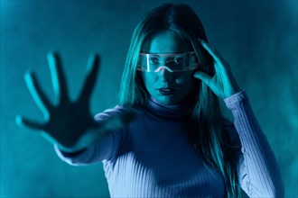 Blonde woman with futuristic glasses gesturing against a blue background