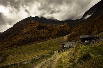 Alpine hut in autumnal mountain landscape with threatening cloudy sky