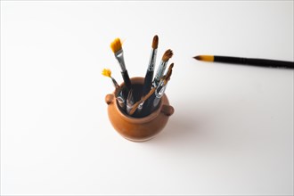 Top view earthenware jar with brushes isolated on a white background
