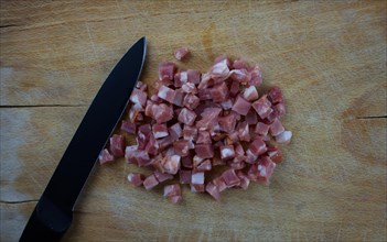 Diced ham and a knife on a wooden board
