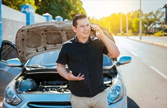 Young man with damaged car calling the mechanic