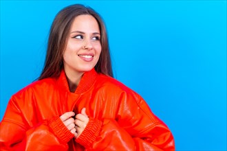 Close up portrait of young caucasian woman in red windbreaker isolated on blue background