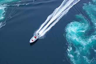 Powerboat between huge whirlpools and eddies in the water of a fjord