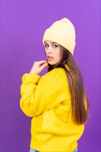 Close up portrait of young caucasian woman in wool sweater isolated on yellow studio background