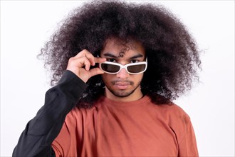 Portrait wearing sunglasses and looking at the camera. Young man with afro hair on white background