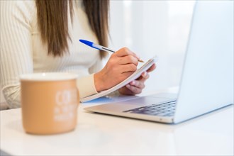 Hands of a woman working with a computer sitting at home with the agenda