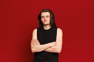 Studio portrait of young handsome man with long black hair over red background