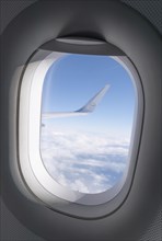 View from a window onto the wing of a Lufthansa aircraft over a sea of clouds