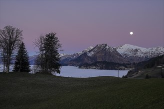 Full moon over mountain peak at dawn