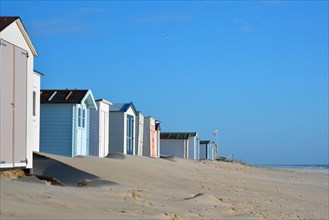 Row of beach huts on the beach of island Texel in the Netherlands with blue sky on sunny day