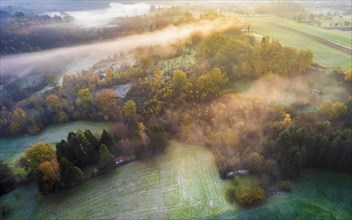 Drone view of sunrise over forest and rural landscape in autumn