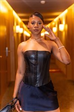 Medium shot of wealthy black ethnic woman posing in hotel room corridor