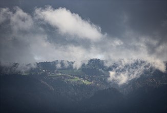 Cloudy forested mountains with mountain village