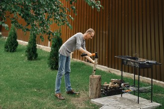 Man chopping wood near barbecue
