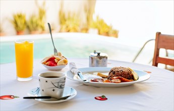 Close-up of a traditional breakfast on a table with a swimming pool in the background. Morning breakfast on the table near a swimming pool