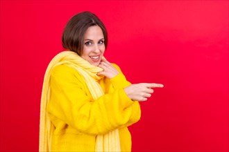 Attractive woman smiling pointing fingers at copy space on red background