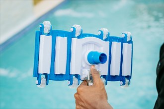 Hand holding swimming pool sweeper head. Close up of hand holding swimming pool sweeper. Pool cleaning and filtration tools concept