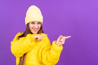 Attractive woman smiling pointing fingers at copy space on purple background