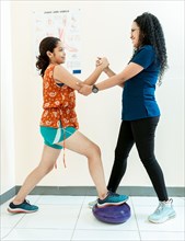 Balance physiotherapy on disc. Physiotherapist woman helping patient on balance disc. Physiotherapist with patient doing balance exercises