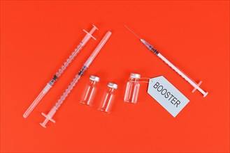Corina virus booster vaccination concept with vials and syringes on red background