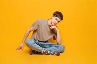 A young adult man dressed in rolled jeans and olive t shirt