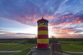 Pilsum lighthouse at sunset on the dyke near Greetsiel in the Krummhoern region on the East Frisian North Sea coast