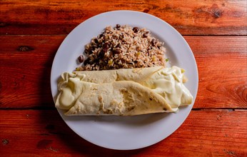 Top view of traditional gallo pinto with Quesillo served on wooden table. Plate of nicaraguan gallopinto with quesillo on the table. typical nicaraguan foods