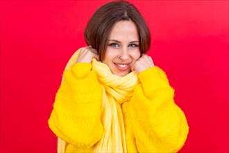 Beautiful young woman wearing warm yellow wool sweater on red background. cold winter portrait