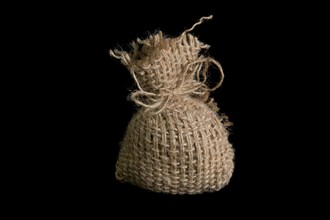 A small jute bag on a black background. In studio