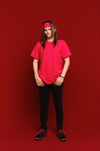 Full body indoor portrait of positive good-looking hipster guy wearing red band on head