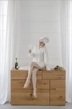 Portrait of an attractive woman with a towel on her head drinking champagne