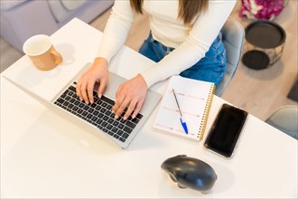 Hands of a woman working with a computer sitting at home smiling