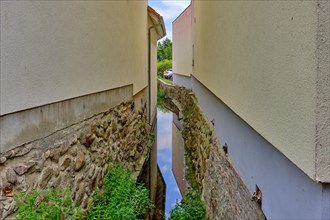 Narrow ravine between two houses through which a small stream flows