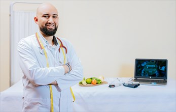 Portrait of smiling male nutritionist at his workplace. Smiling nutritionist doctor with crossed arms in her office. Portrait of smiling professional nutritionist