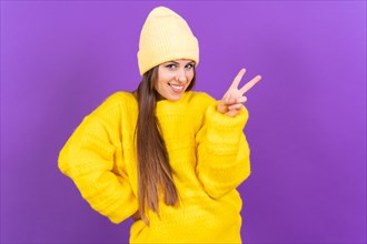 Young woman isolated on purple background smiling and showing victory sign