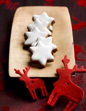 Cinnamon stars on wooden board with little reindeer made of fabric