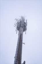 Mobile phone mast covered in snow and ice photographed from below