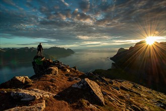 Man standing alone in sunset mountains hiking outdoor active vacations traveling. Adventure lifestyle. Senja