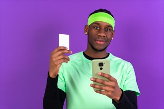 Black ethnic man with a phone in green clothes on a pink background