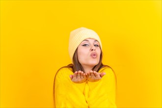 Photo portrait of a young woman blowing a kiss isolated on a yellow background