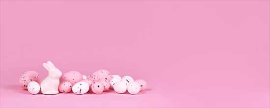 Banner with white and pink Easter eggs with small bunny sculpture on pink background with copy space