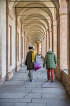 Couple walking through arcades to Colle della Guardia
