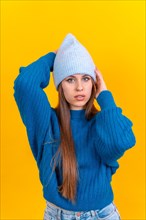 Close up portrait of young caucasian woman in blue wool sweater isolated on yellow background