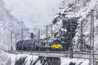 Goods train with tank wagon driving through the snow