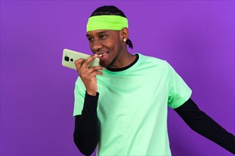 Black ethnic man with a phone in green clothes isolated over purple background