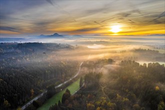 Drone view of sunrise over forest and rural landscape in autumn