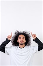 Pointing above a copy paste space. Young man with afro hair on white background