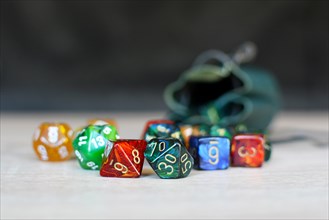Different colorful role playing dice on table with blurry storage leather bag in background