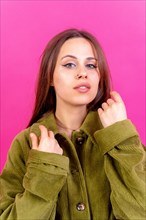 Close up portrait of young caucasian woman in green trench coat isolated on pink background