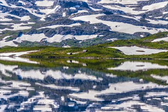Reflection of partly snow-covered mountains in Lake Stavatn in Haukelifjell
